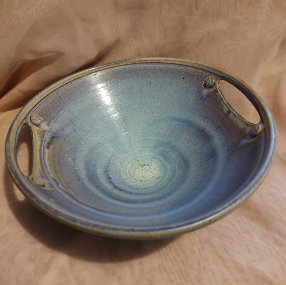 Stoneware pottery on a pedestal with handles.